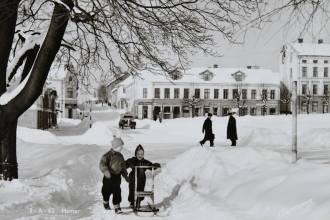 Foto (1950-1955): Postkort fra Hamar by. Stortorget og Strandgata. I bakgrunnen Aasgården med Cafe ”Nor”.