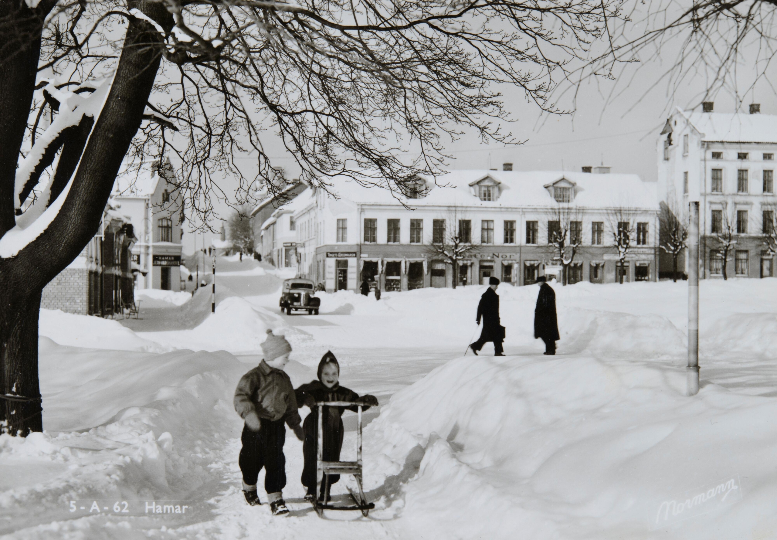 Foto (1950-1955): Postkort fra Hamar by. Stortorget og Strandgata. I bakgrunnen Aasgården med Cafe ”Nor”.